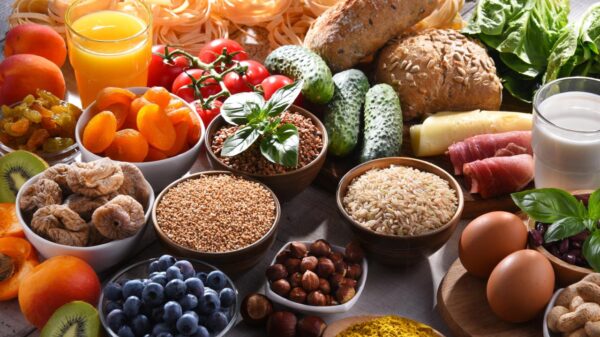 Vários alimentos saudáveis como frutas, legumes e grãos em cima de uma mesa de madeira.