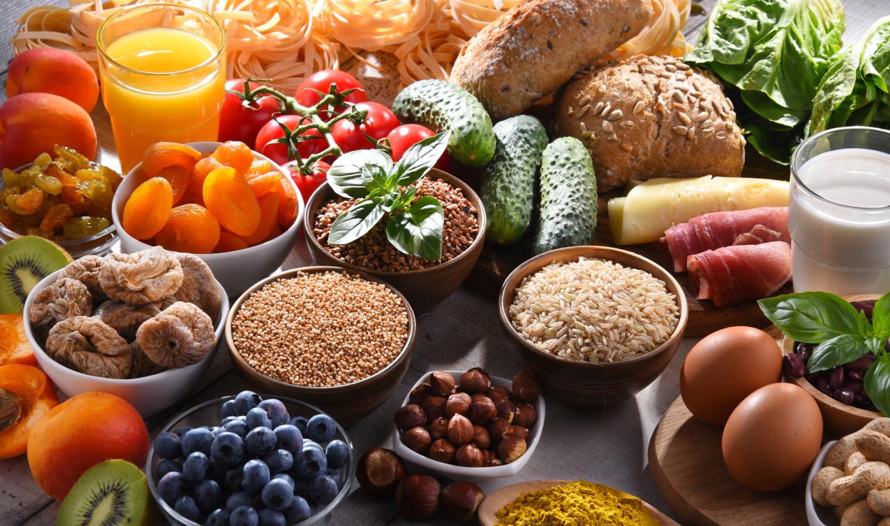 Vários alimentos saudáveis como frutas, legumes e grãos em cima de uma mesa de madeira.