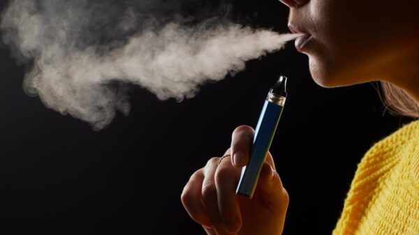 Foto mostra uma pessoa fumando vape enquanto sai fumaça.