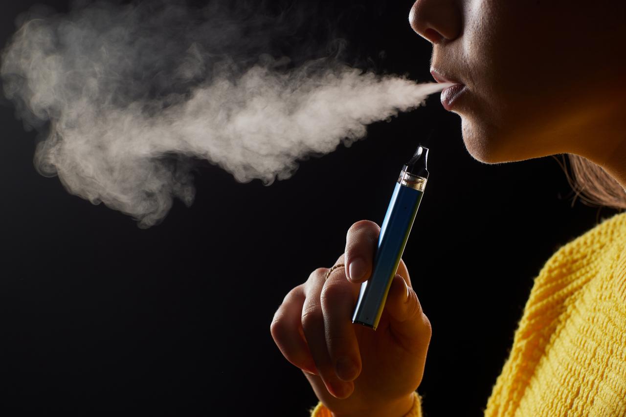 Foto mostra uma pessoa fumando vape enquanto sai fumaça.