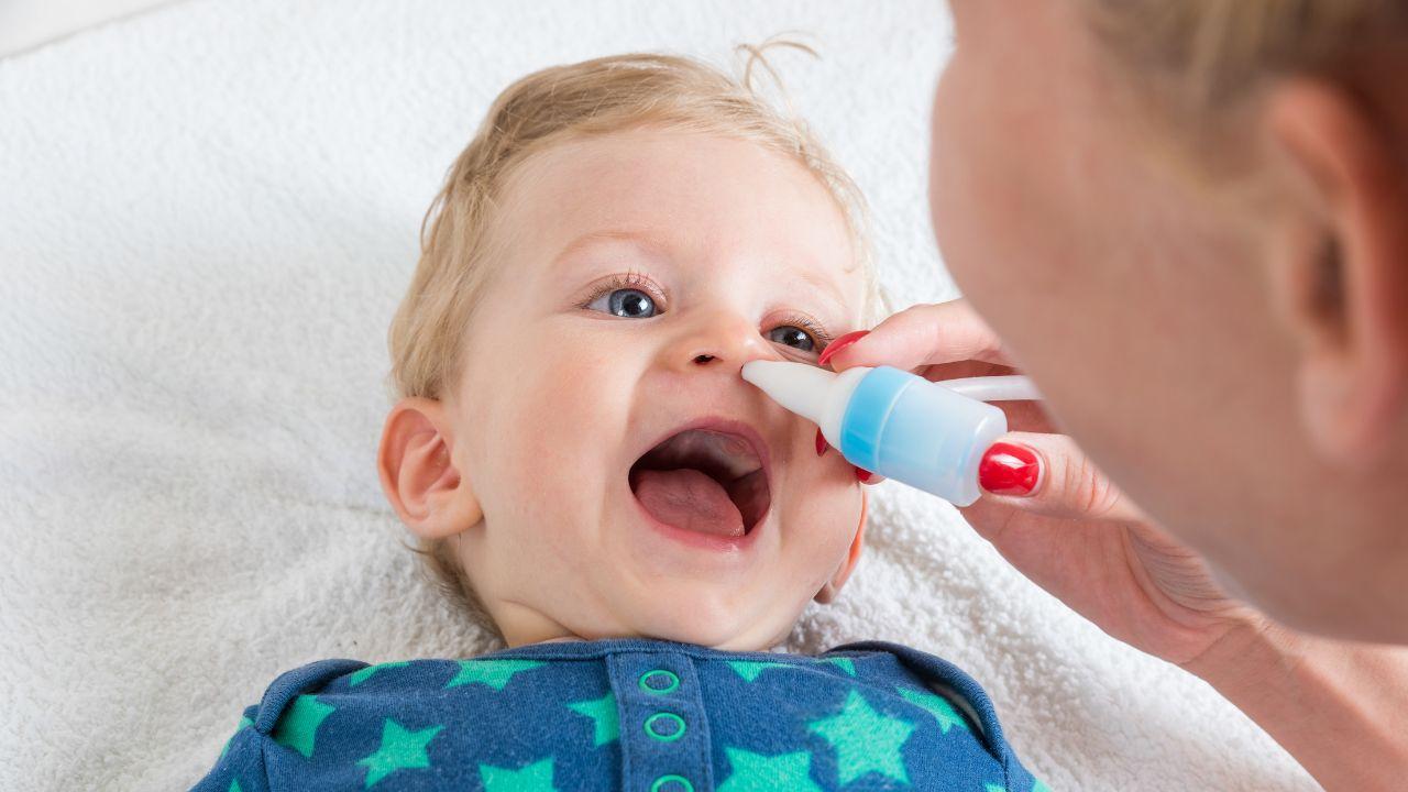 Imagem de uma mulher colocando um produto no nariz de um bebê