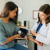 Imagem de uma médica aferindo a pressão de uma mulher jovem