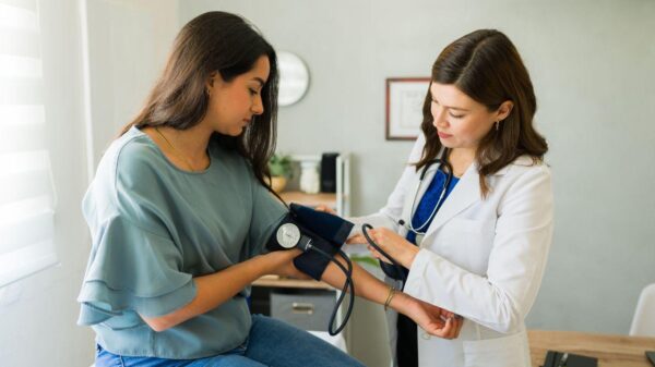 Imagem de uma médica aferindo a pressão de uma mulher jovem