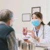 Imagem de uma médica consultando um paciente homem idoso