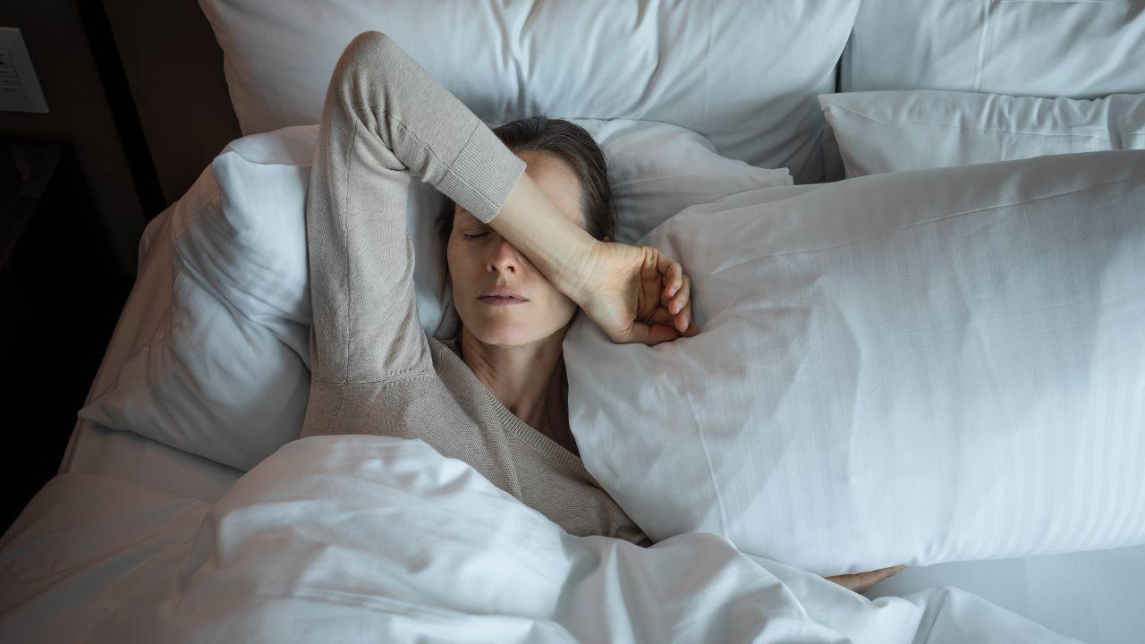 Imagem de uma mulher na cama com o braço apoiado na testa