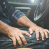 Imagem de um homem no banco do motorista de um carro com as mãos na perna