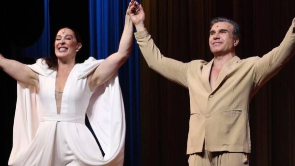 Mostra Claudia Raia e o marido Jarbas Homem de Mello juntos no palco com as mãos unidas pra frente.