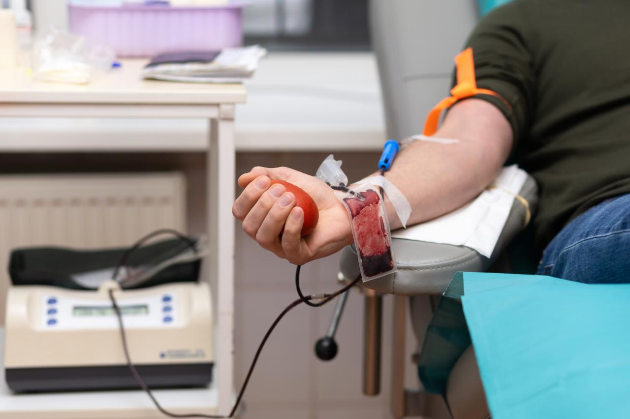 Foto mostra pessoa doando sangue.