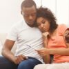 Casal sentados no sofá com rosto preocupado.