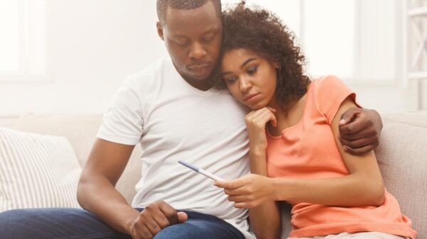 Casal sentados no sofá com rosto preocupado.