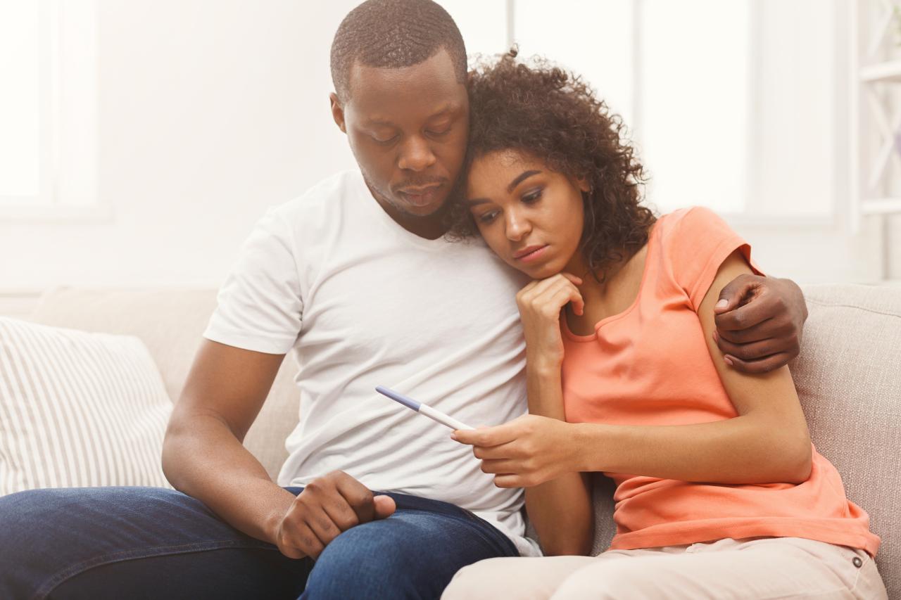 Casal sentados no sofá com rosto preocupado.