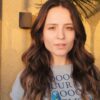 Larissa Manoela. Mulher branca, cabelo castanho ondulado, sorrindo ao ar livre.