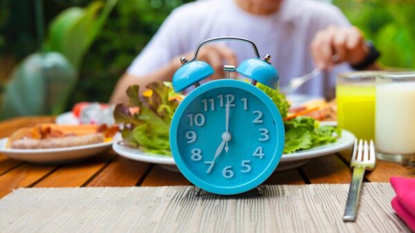 Imagem de um relógio azul em cima de uma mesa com pratos de comida atrás