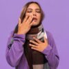 Imagem de uma mulher com cachecol roxo e a mão no nariz