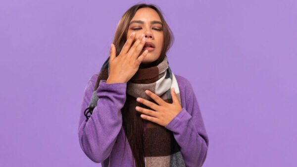 Imagem de uma mulher com cachecol roxo e a mão no nariz
