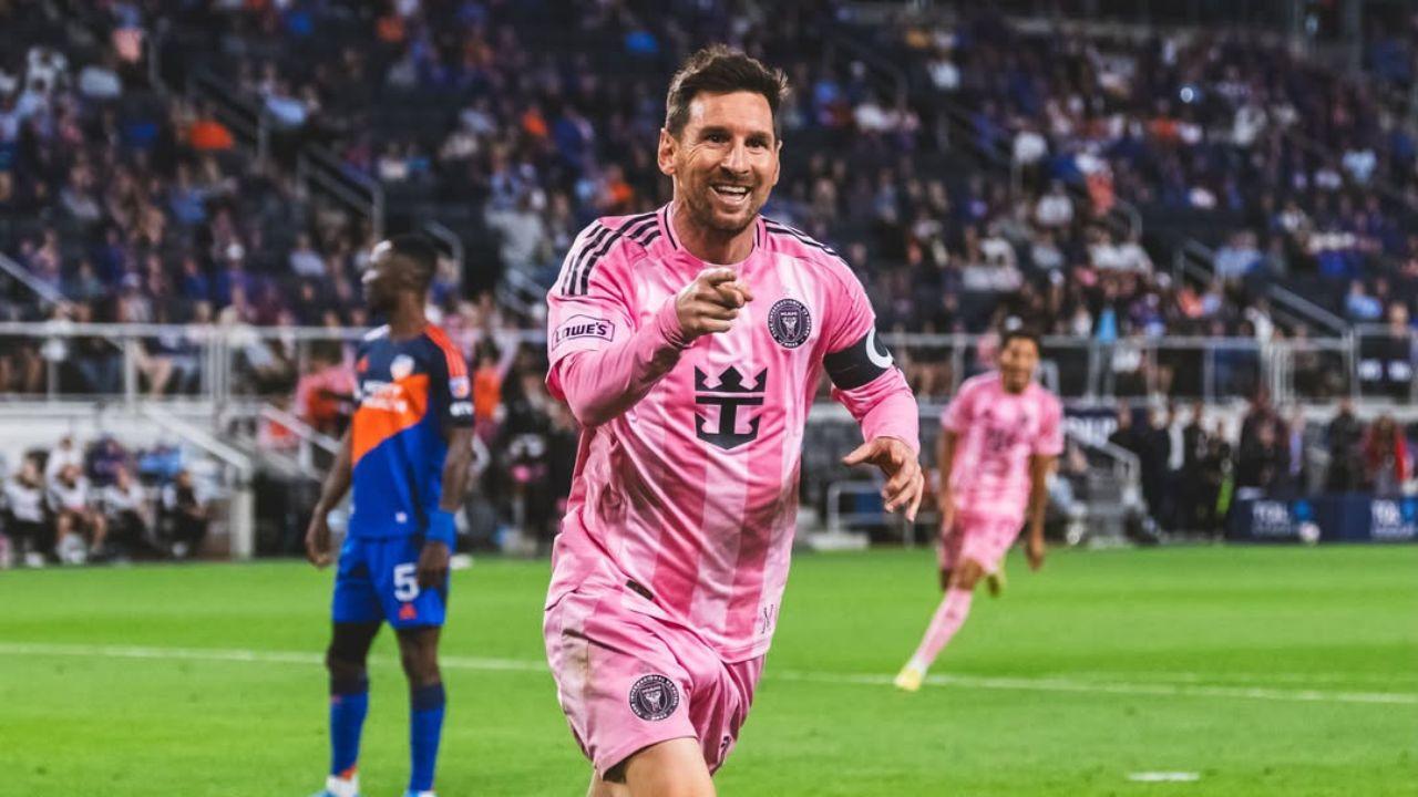 Imagem de Lionel Messi em campo com uniforme rosa apontando para frente comemorando