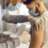 Foto mostra médica aplicando vacina em um paciente.