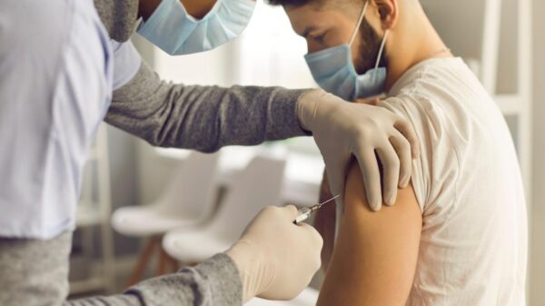 Foto mostra médica aplicando vacina em um paciente.