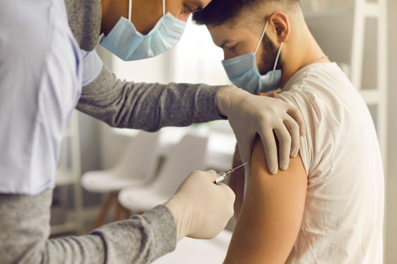 Foto mostra médica aplicando vacina em um paciente.