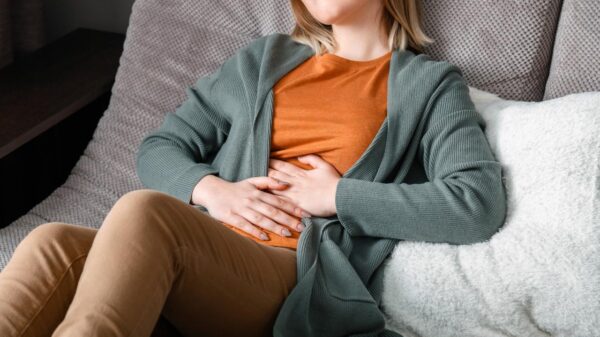 Mulher deitada no sofá com a mão na barriga.