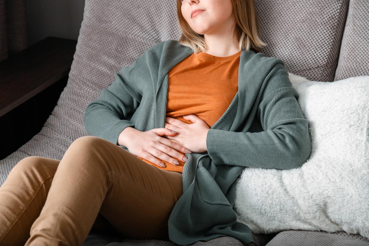 Mulher deitada no sofá com a mão na barriga.