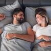 Mulher e homem deitados na cama sorrindo um para o outro.