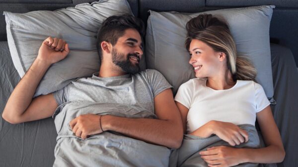 Mulher e homem deitados na cama sorrindo um para o outro.