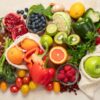 Foto mostra várias frutas, legumes em cima de uma mesa.