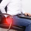 Homem sentado numa cadeira com um notebook no colo.