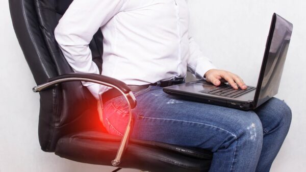 Homem sentado numa cadeira com um notebook no colo.