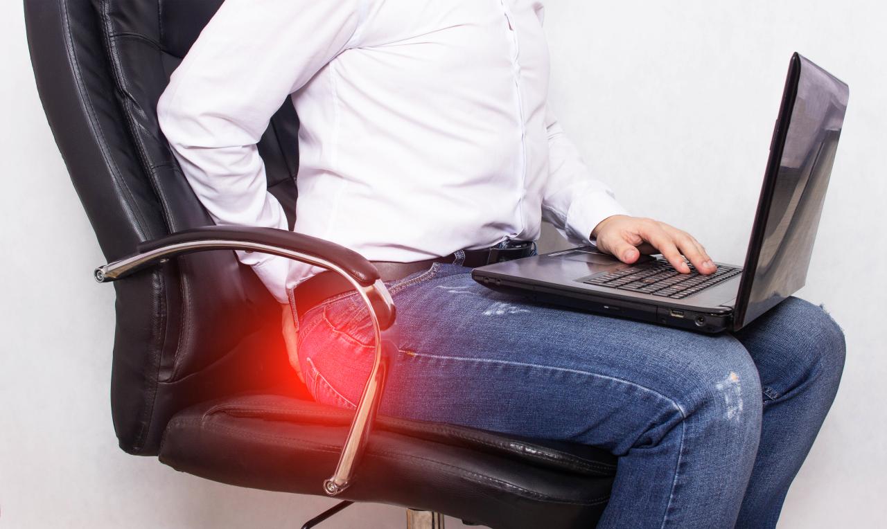 Homem sentado numa cadeira com um notebook no colo.