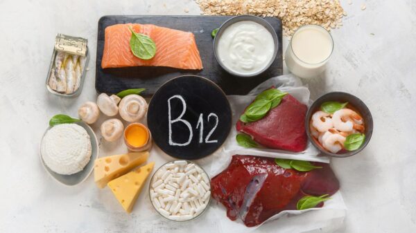 Foto mostra vários alimentos que tem B12 e um cartaz no meio escrito B12.