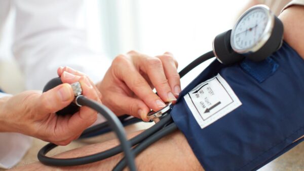 Foto mostra médica aferindo a pressão de um paciente com o aparelho.