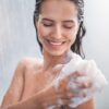 Imagem de uma mulher tomando banho com uma bucha cheia de espuma