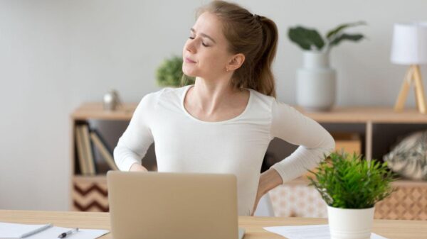 Imagem de uma mulher com dor nas costas na mesa de trabalho