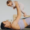 Imagem de uma mãe fazendo Yoga segurando um bebê
