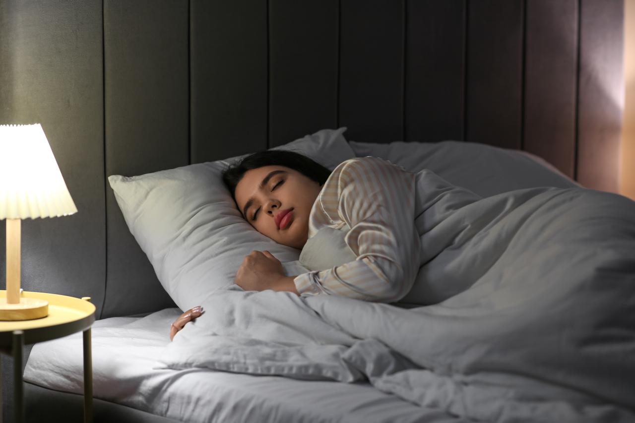 Mulher dormindo em cama com lençol branco.