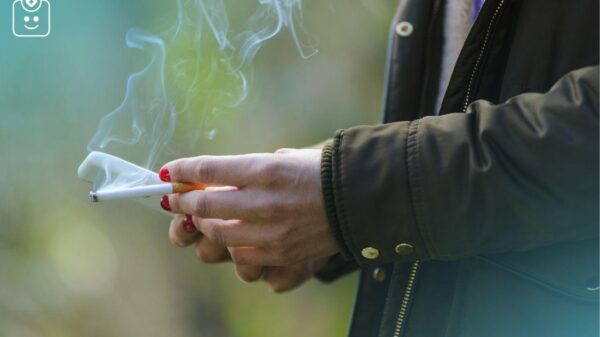 Foto mostra uma mão com esmalte nas unhas segurando um cigarro.