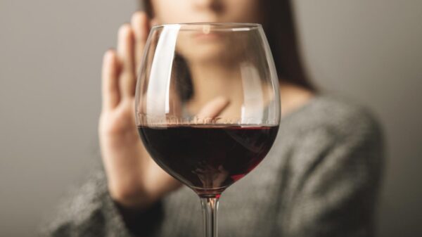 Mulher recusando uma taça de vinho tinto.