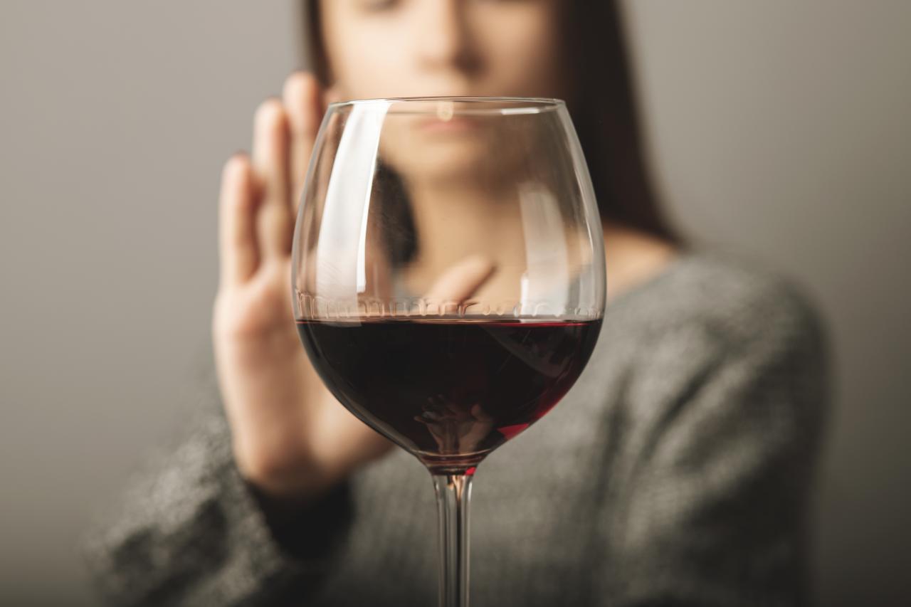 Mulher recusando uma taça de vinho tinto.