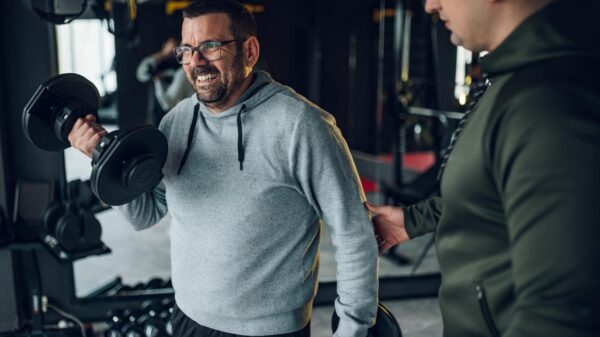 Homem barrigudo fazendo biceps com halteres.