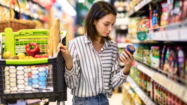 Mulher lendo os rótulos de alimentos na frente da prateleira do supermercado.