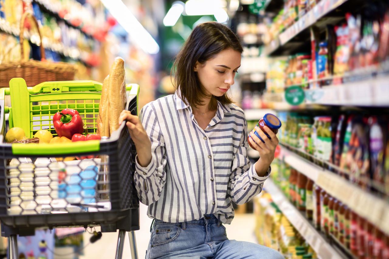 Mulher lendo os rótulos de alimentos na frente da prateleira do supermercado.