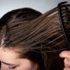 Pessoa penteando o cabelo da mulher com pente.