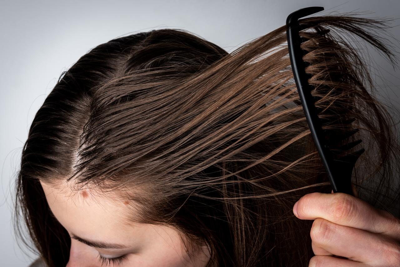 Pessoa penteando o cabelo da mulher com pente.
