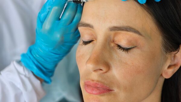 Mulher com o olho fechado enquanto uma médica aplica botox na testa dela.