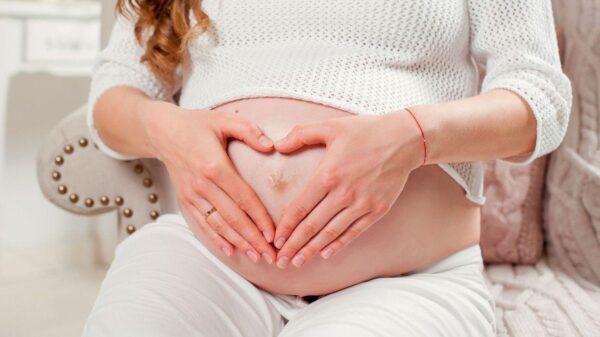 Imagem de uma grávida fazendo um coração com as mãos na barriga