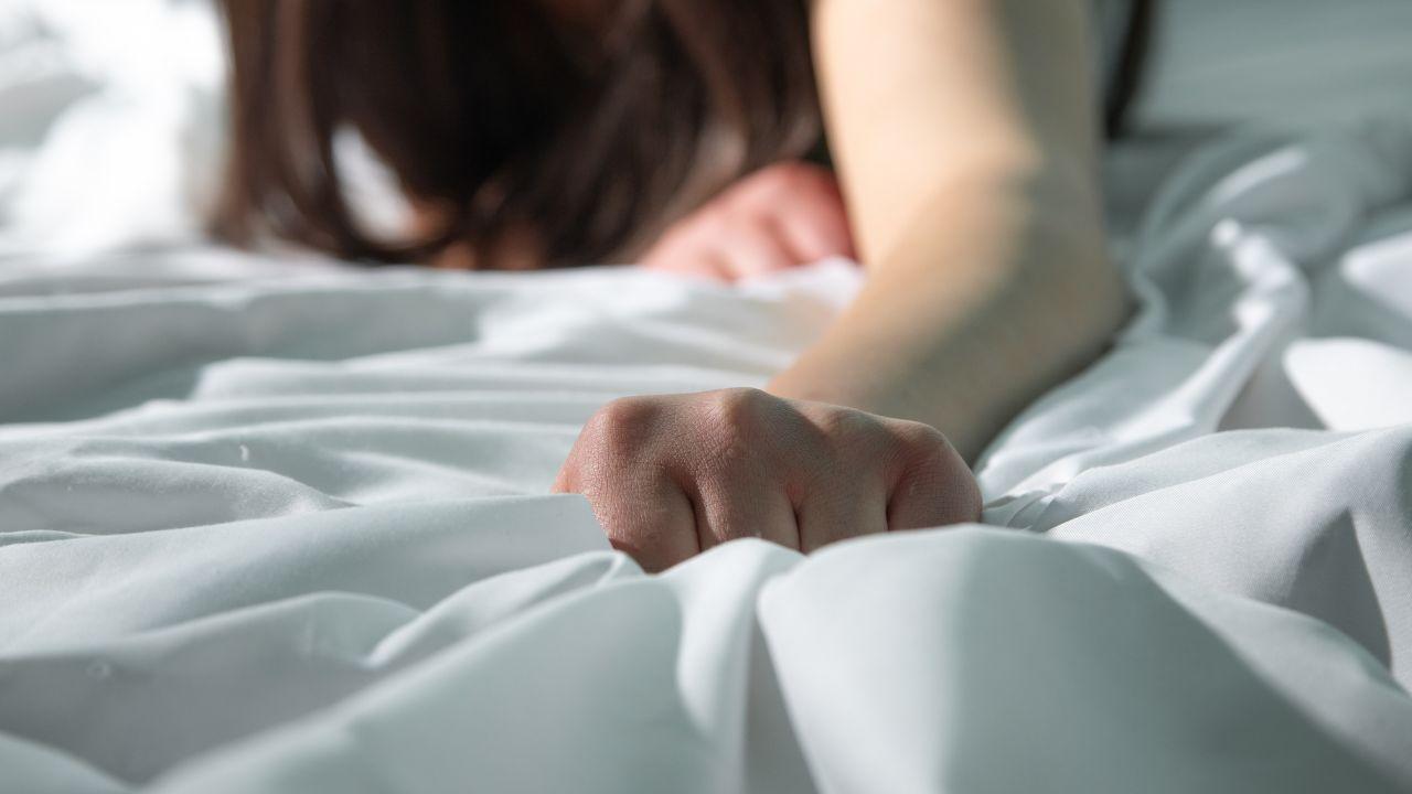Imagem de uma pessoa segurando o lençol da cama