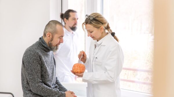 Foto mostra um homem em um consultório médico com uma médica cuidando dele.