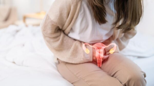 Mulher sentada na cama com dor no útero e um desenho de útero na barriga dela.